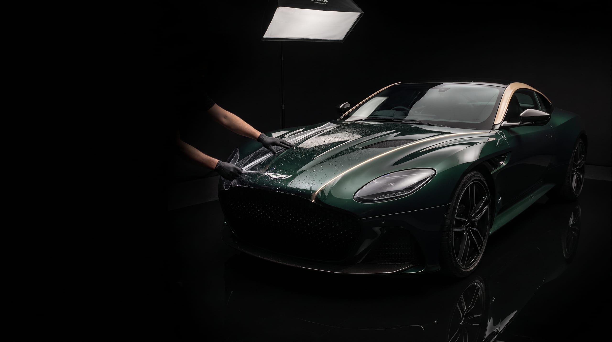 Paint Protection Film wordt op de motorkap van een donkergroene Aston Martin DBS aangebracht