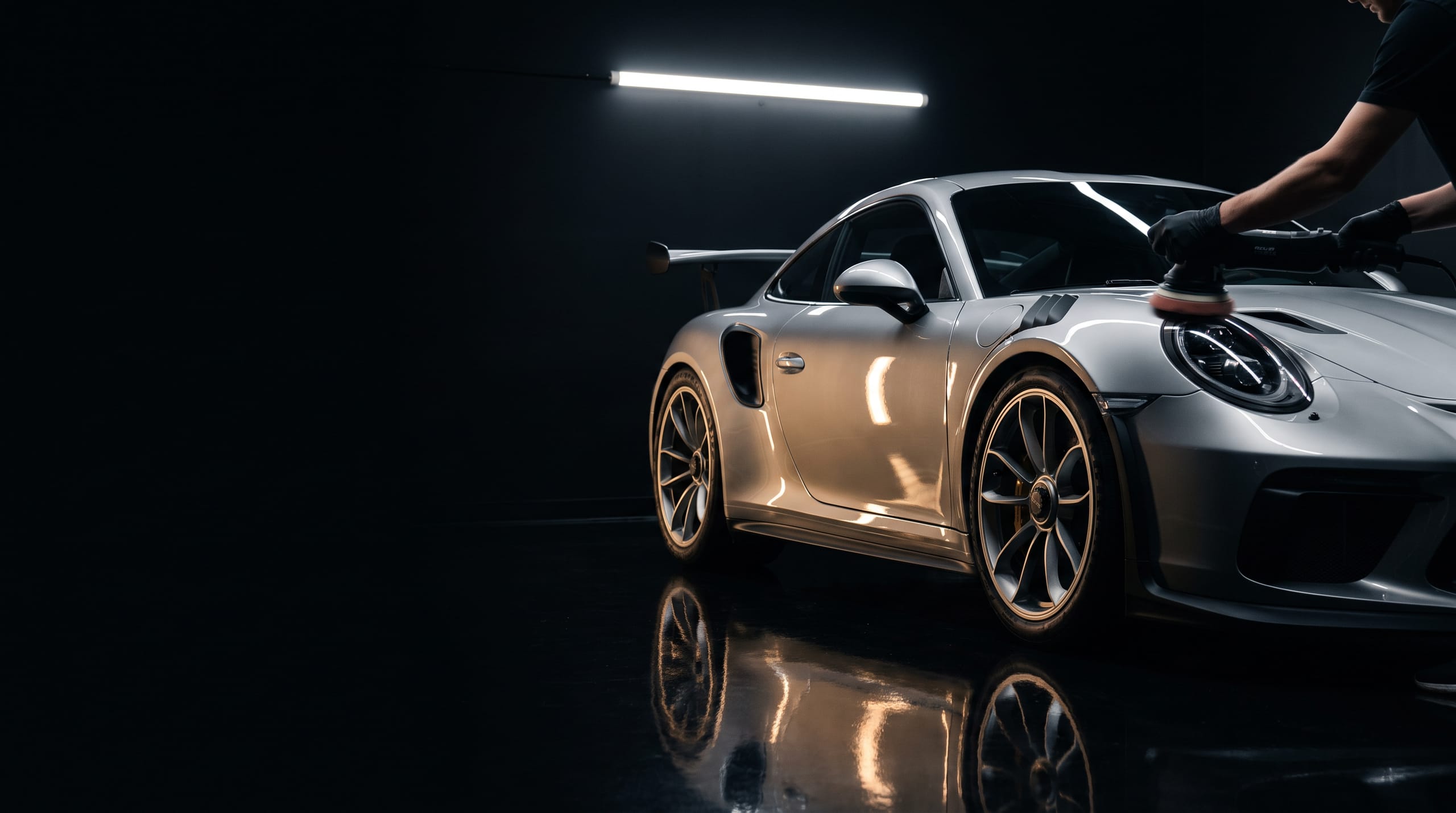 Porsche 911 GT3 RS in zilver tijdens paint correction met polijstmachine op het voorspatbord