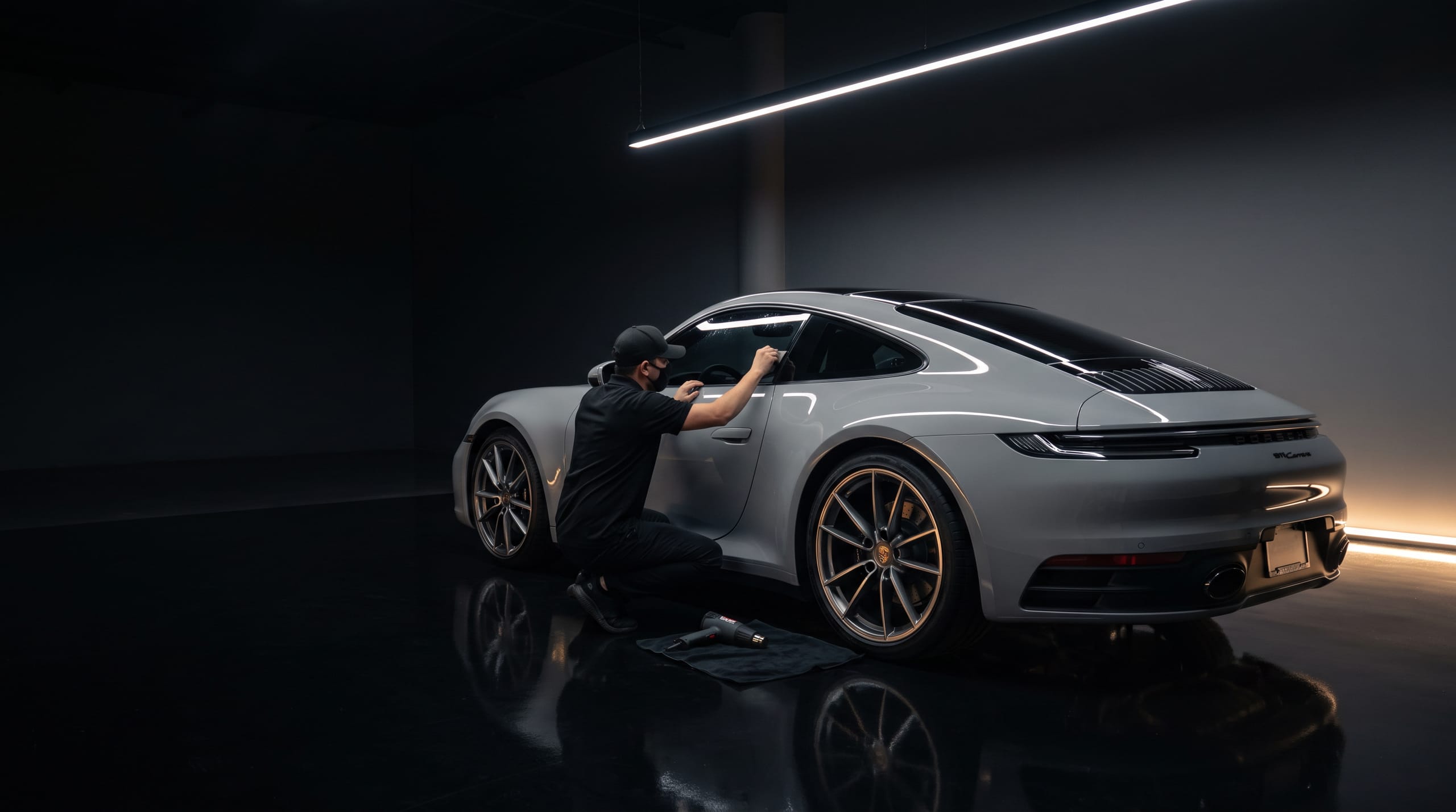 Technicus brengt raamfolie aan op een grijze Porsche 911 Carrera in de studio